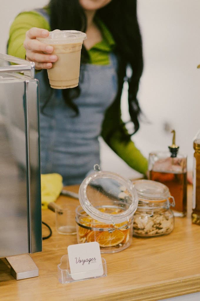 Barista presenting iced coffee with artisan garnishes - Premium cold beverages for event catering